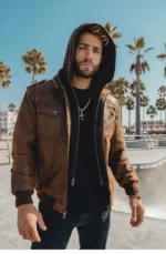 Portrait d'homme avec une veste en cuir marron et col capuche, look confiant et rock.