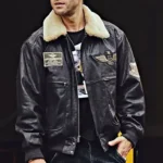 Homme portant un blouson en cuir foncé, style aviateur, avec un col en fourrure beige et des écussons militaires, veste homme.