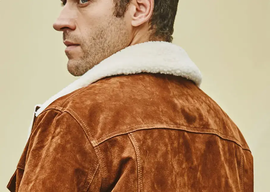 Texture détaillée du blouson en cuir marron type aviateur avec poignet boutonné.