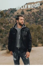 Blouson cuir noir homme avec capuche grise, silhouette tendance branché devant le panneau Hollywood.