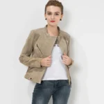Modèle portant une veste biker en daim beige, ouverte, révélant un t-shirt blanc, look décontracté.