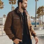 Veste en cuir homme marron, aspect vieilli, portée par un homme au bord de mer, style urbain.