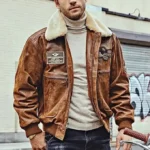 Homme portant un blouson aviateur en cuir marron, col fourrure, écussons militaires, style classique et intemporel.
