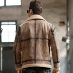 Dos du manteau homme en peau lainée marron, coutures apparentes pour un style authentique.