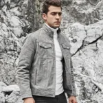 Homme en blouson gris de style motard, légèrement ouvert, révélant un pull à col roulé blanc. Une veste en cuir pour homme polyvalente et chic.