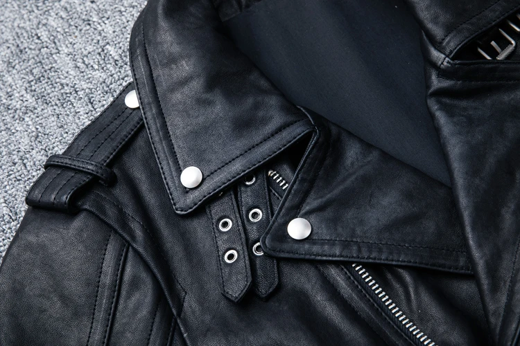 Détail du col et de l'épaule du perfecto en cuir pour homme, avec boutons pression argentés et œillets.