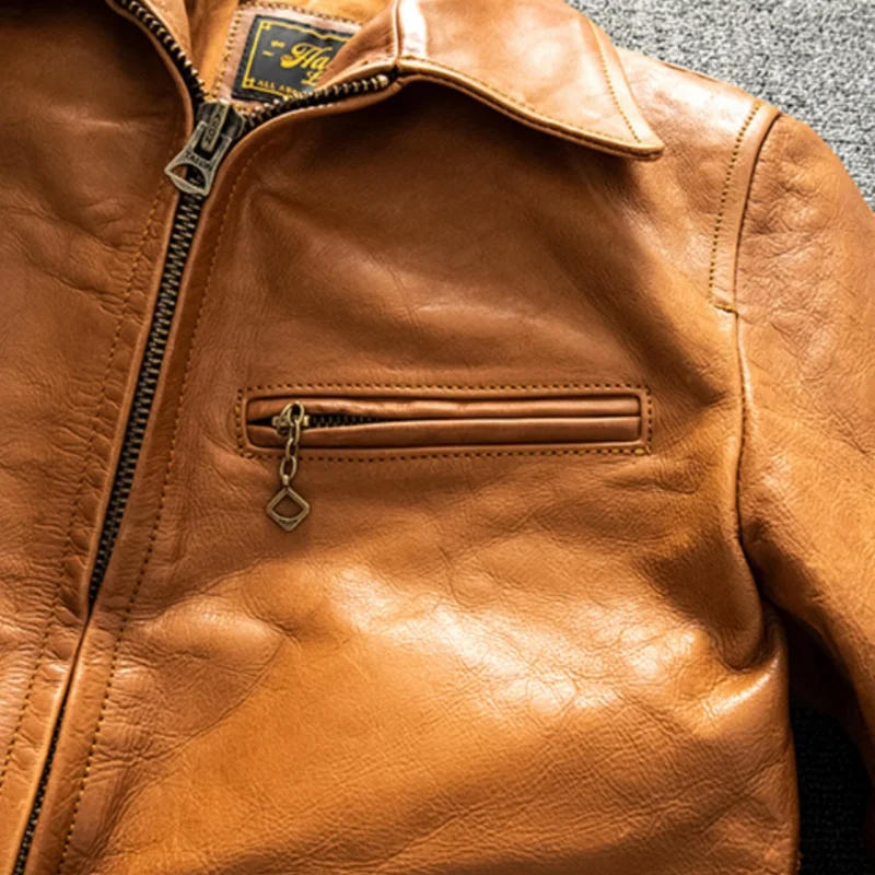 Détail de la fermeture éclair et de la poche poitrine sur cette veste en cuir marron pour homme, élégance et fonctionnalité.