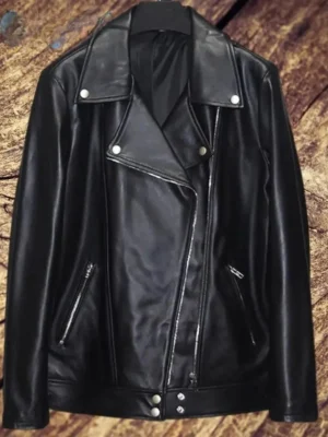 Veste blouson en cuir noir posée sur un cintre devant un fond en bois, un classique de la mode féminine.