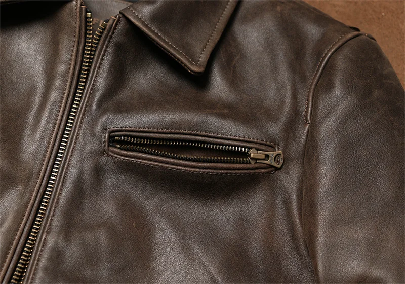 Poche poitrine zippée sur la veste en cuir marron, fermeture éclair robuste en métal, design pratique pour blouson homme.